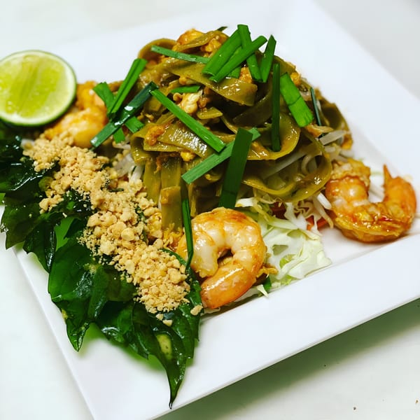 Tiki Tiki Thai Cuisine's Pad See Ew with green noodles, shrimp, crushed peanuts, and a lime wedge.