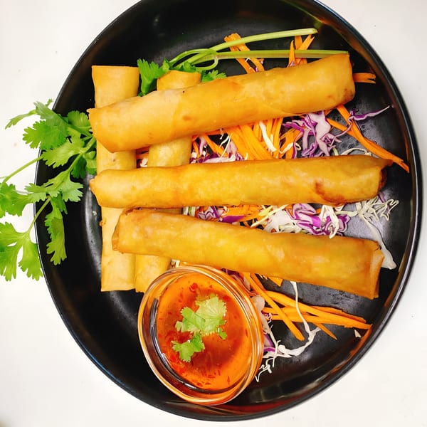 Golden-fried Thai spring rolls with shredded carrots, cabbage, cilantro, and a sweet chili dipping sauce.